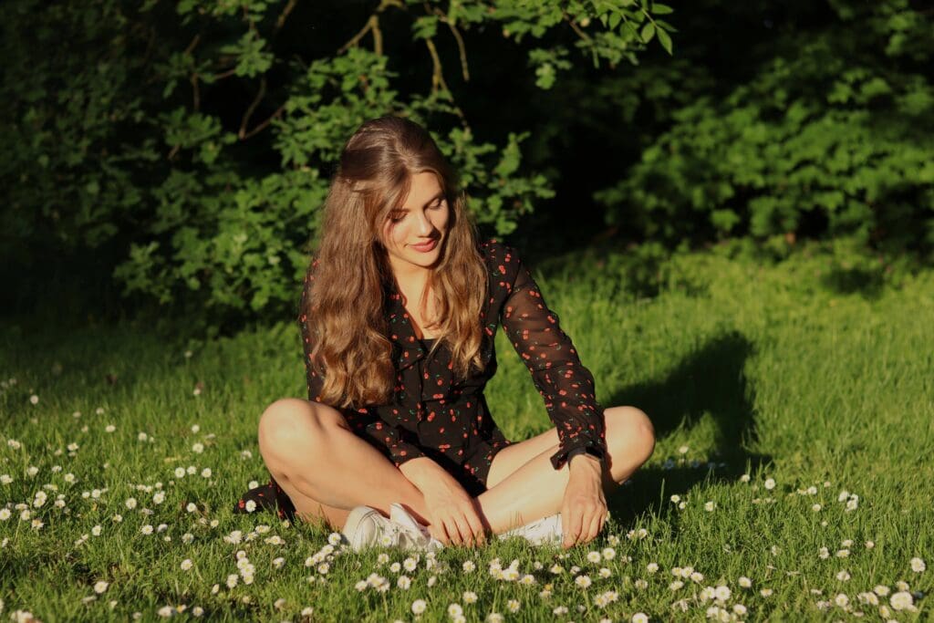 Woman sitting in grass. Control weight by boosting dopamine from connecting with nature