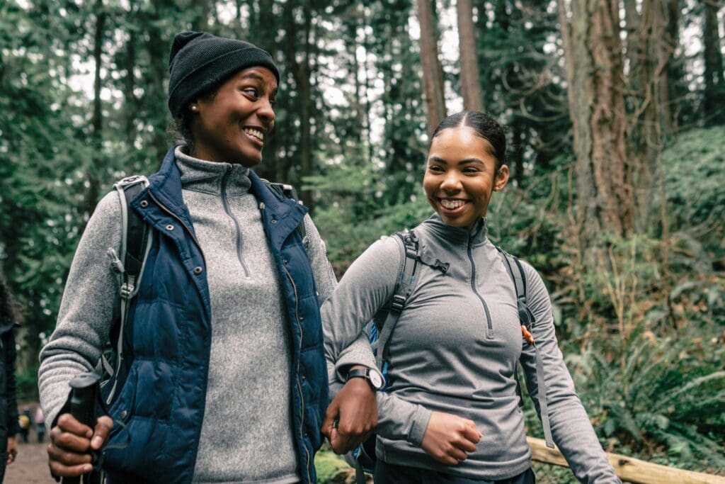 women smiling while hiking in forest together for weight loss